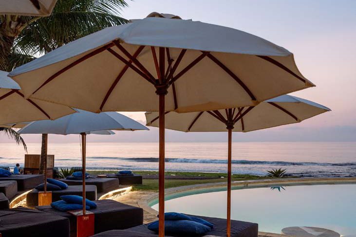 Cream umbrellas and day beds beside the pool at dusk, Komune Resort, East Bali
